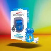 The Charged Big O Cock Ring from Screaming O is showcased in electric blue alongside its branded packaging, complete with product details. The set includes a USB charging cable, all presented against a vibrant gradient background featuring colors like red, yellow, and green.